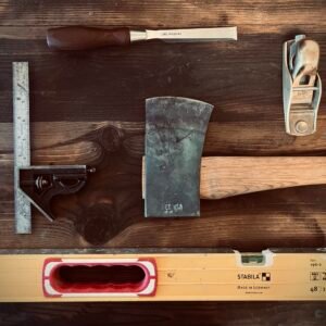 5 Heirloom-Quality Gifts Every Tool Lover Will Treasure for Life Heirloom-quality hand tools including a forged axe, wood chisel, hand plane, square, and Stabila level arranged on a wooden workbench