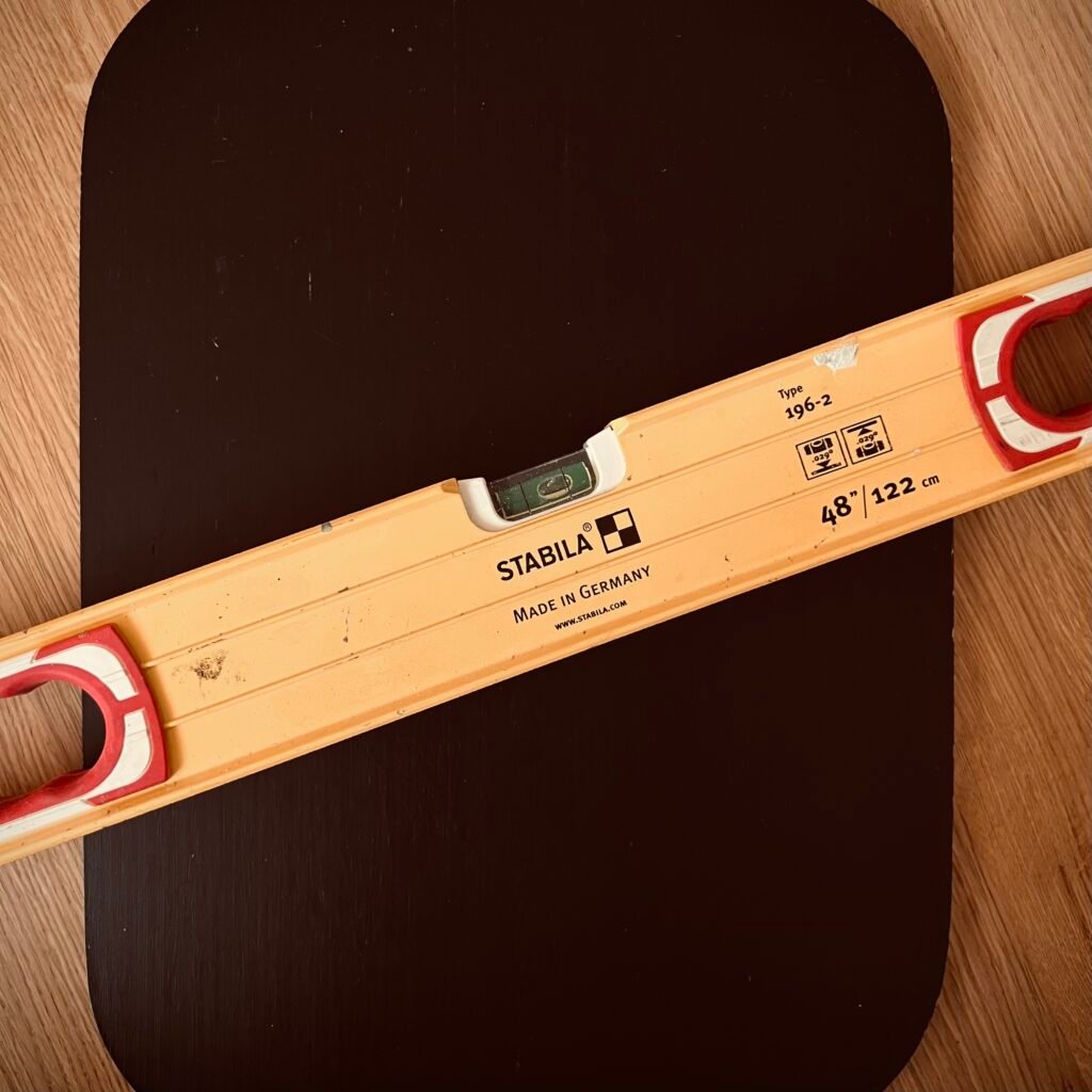 A well-used Stabila level resting on a dark wood surface, representing heirloom quality tools built for precision and longevity.