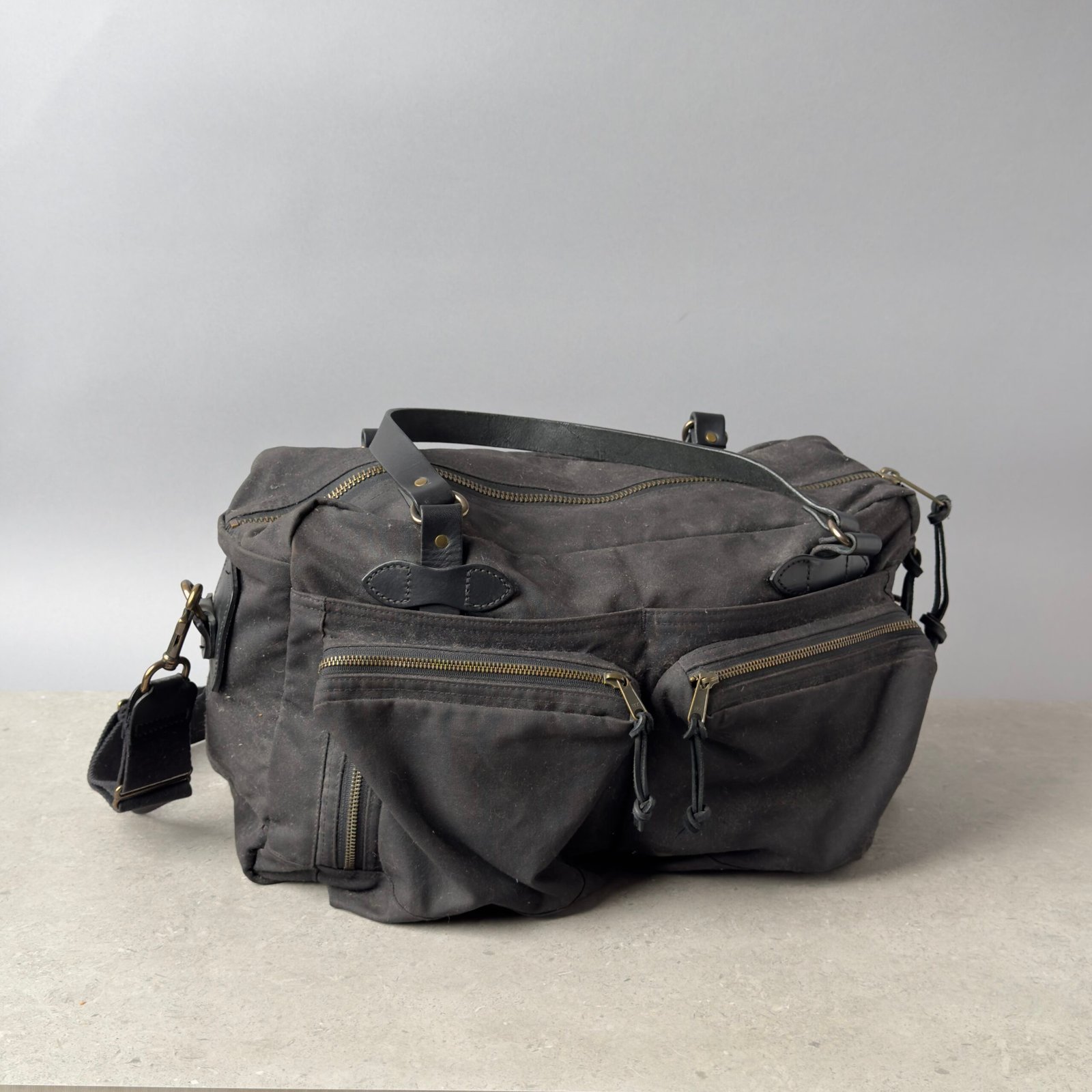 Filson 48 Hour Tin Cloth duffle bag in dark waxed canvas with leather handles and front zip pockets