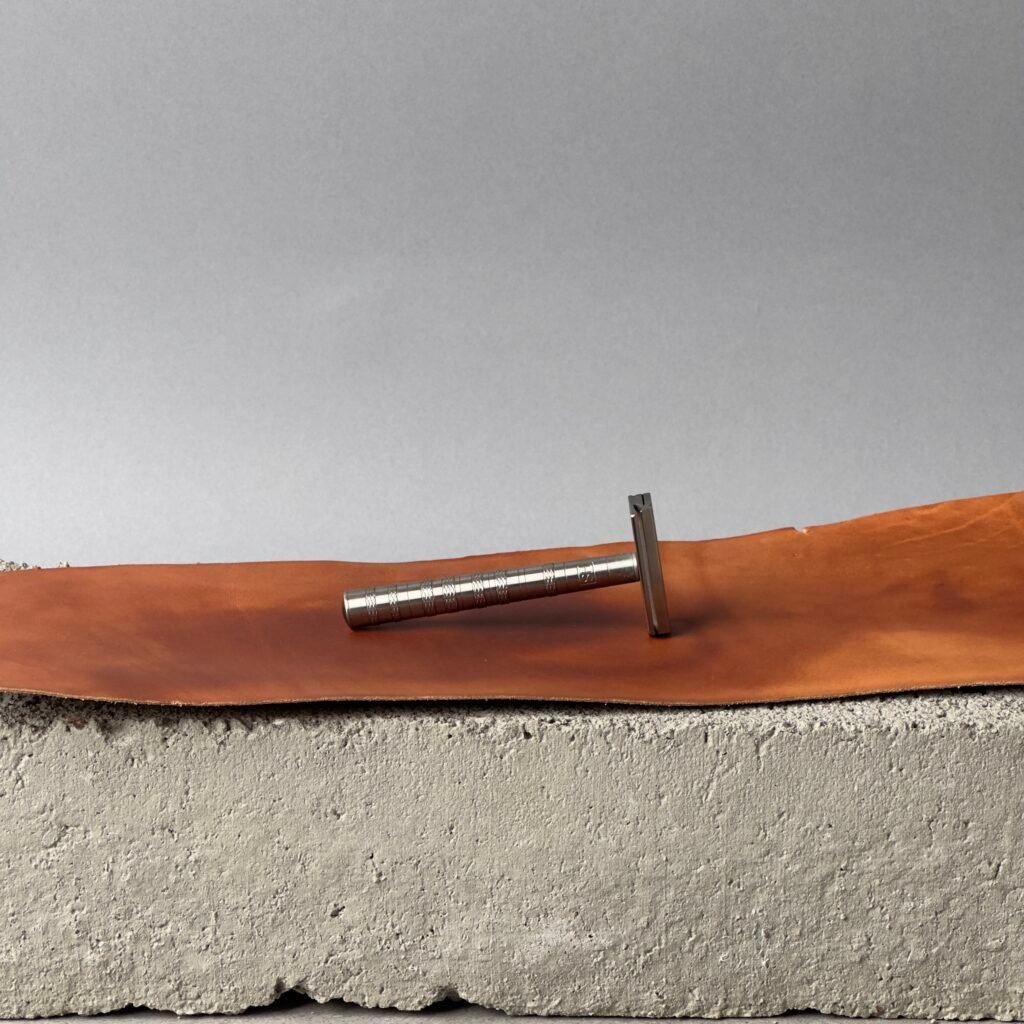 Henson Ti22 titanium safety razor on a leather surface against a neutral background